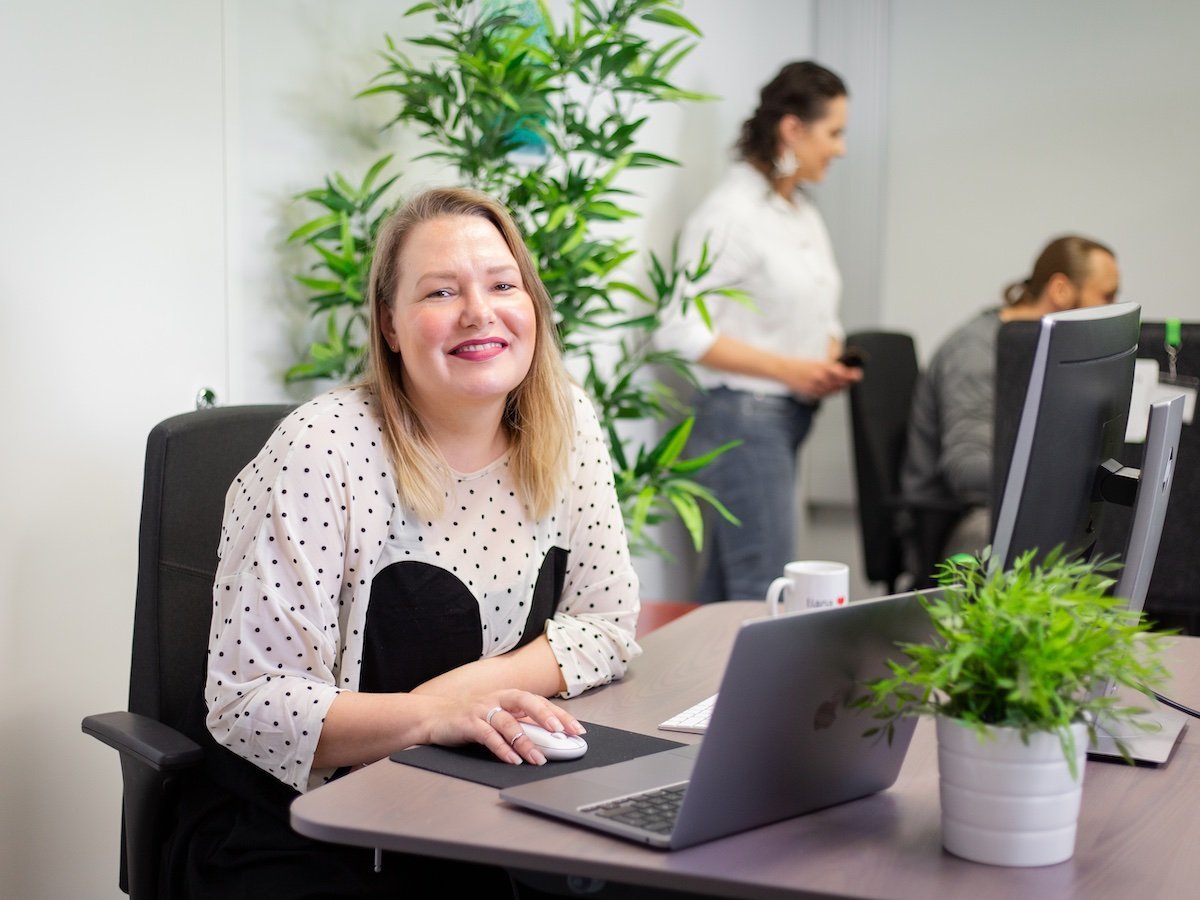 Une personne souriante utilisant l'outil de newsletter LianaMailer sur son ordinateur portable.