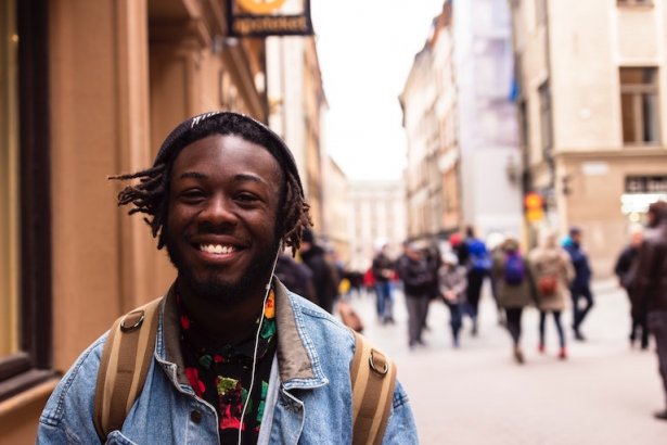 Un étudiant souriant marche dans la rue tout en écoutant de la musique